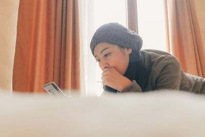 Low angle view of woman using digital tablet while lying on bed