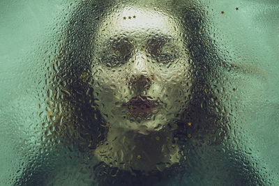 Close-up of woman seen through wet glass
