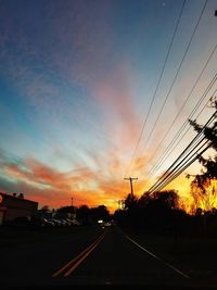 Road by silhouette trees against sky during sunset