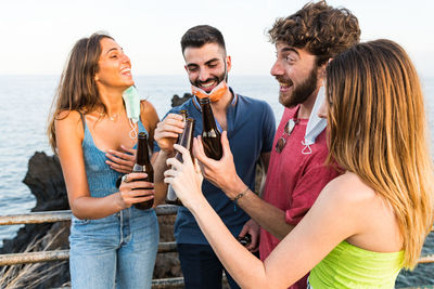 Smiling friends holding drinks standing outdoors