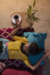 High angle view of woman using digital tablet while lying on sofa