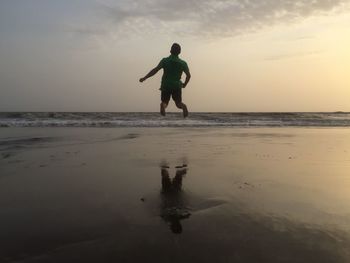 Silhouette man standing on beach against sky during sunset