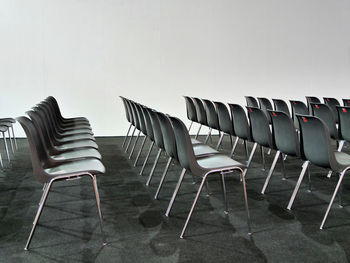 Empty chairs in row against wall