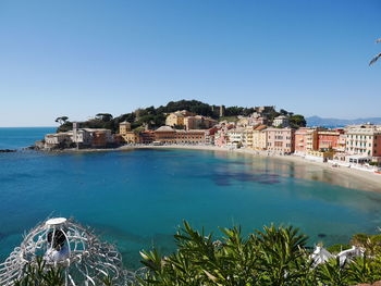 Buildings by sea against clear sky