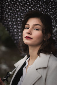 Woman looking away while holding umbrella