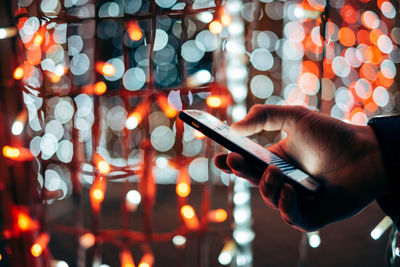 Close-up of hand using mobile phone at night