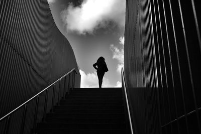 Low angle view of silhouette woman walking on steps against sky