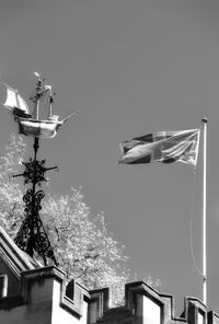 Low angle view of flags on building against clear sky