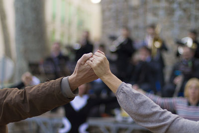 Cropped image of people holding hands outdoors