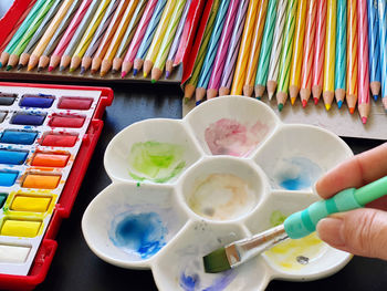 High angle view of hand holding multi colored paints