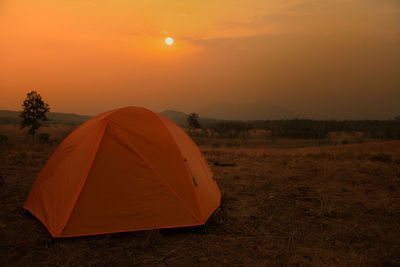 Tent on field against orange sky