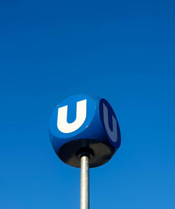 Low angle view of road sign against clear blue sky