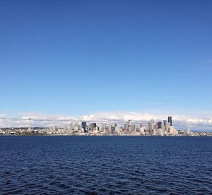 City at waterfront against blue sky