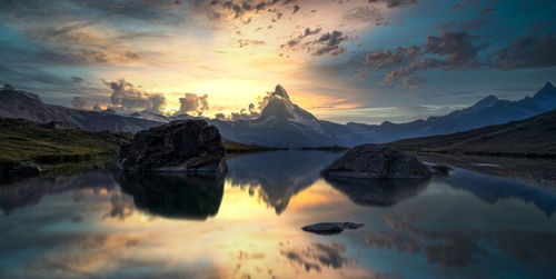 Scenic view of lake and mountains against sky during sunset