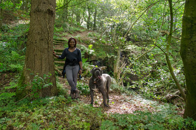 Man and dog walking on road amidst trees