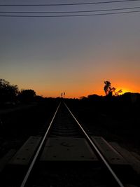 Railway tracks against clear sky during sunset