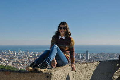 Full length of woman sitting on retaining wall