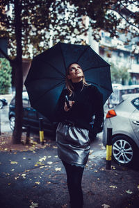 Woman with umbrella standing on street in rain