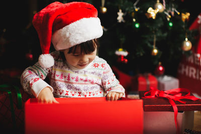 Smiling girl looking in christmas present at home