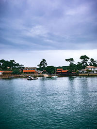 Buildings by river against sky