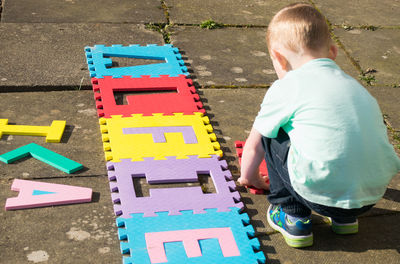 High angle view of boy arranging alphabets on street