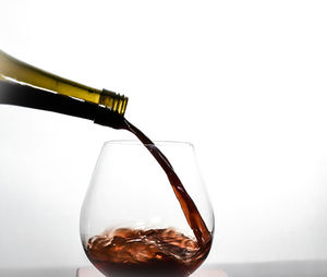 Close-up of wineglass on glass against white background