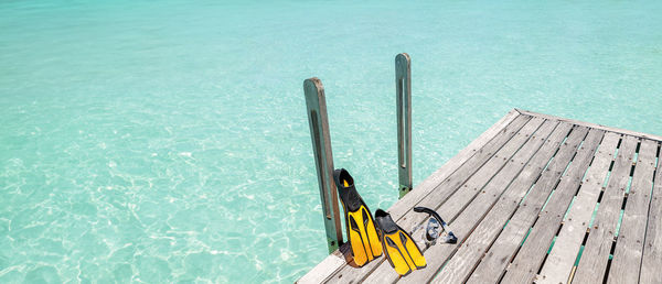 Yellow fins and snorkel, snorkeling equipment on a wooden pier facing the sea., copy space