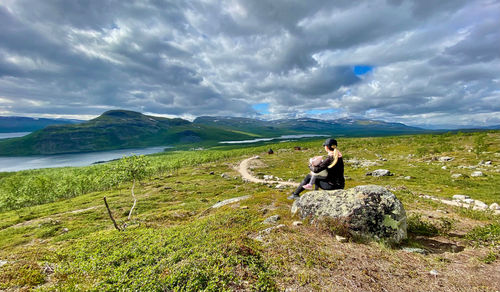 Full length of man sitting on rock against sky