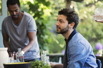 Side view of man sitting on porch at log cabin during summer party