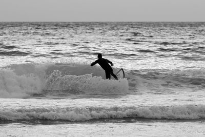 Man surfboarding on sea against sky