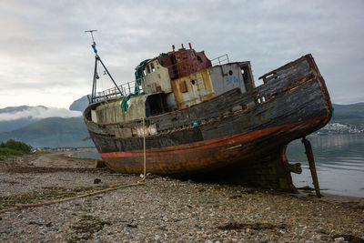 Abandoned boat moored on sea against sky