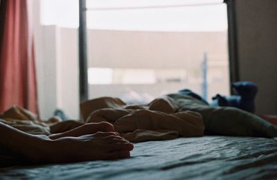 Low section of man relaxing on bed at home