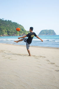 Rear view of man on beach against clear sky