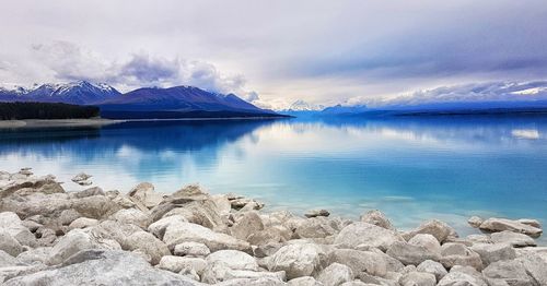 Scenic view of lake by mountains against sky