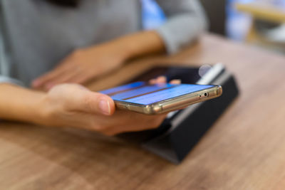 Midsection of person using mobile phone on table