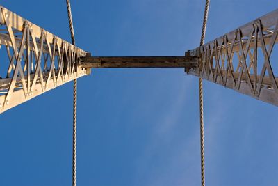 Low angle view of suspension bridge against blue sky