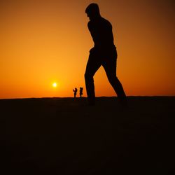 Silhouette man standing against orange sky during sunset