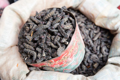 High angle view of dried silkworms in container and sack