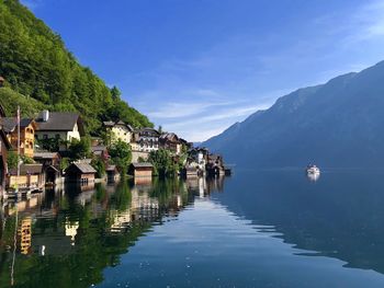 Scenic view of lake by buildings and mountains against sky