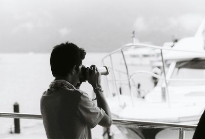 Rear view of man photographing boat