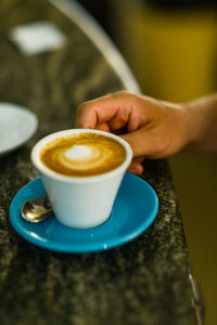 Ma holding cup of espresso coffee cappuccino close up overhead s