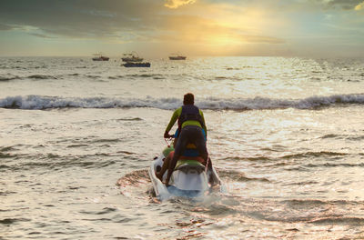 Rear view of man on beach against sky during sunset