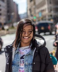 Portrait of smiling young woman on street in city