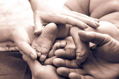 Close-up of mother and father hands holding baby girl feet