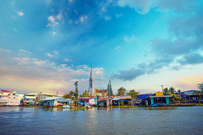 Scenic view of river by buildings against sky