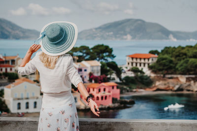 Rear view of woman looking at cityscape against sky