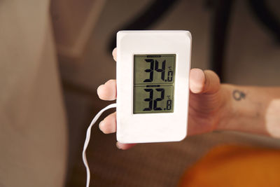 Woman holding thermostat at home