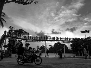 People riding bicycles on street against sky