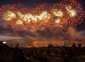 People watching firework display in city at night