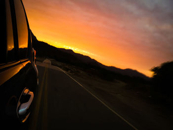 Close-up of car on road against sunset sky